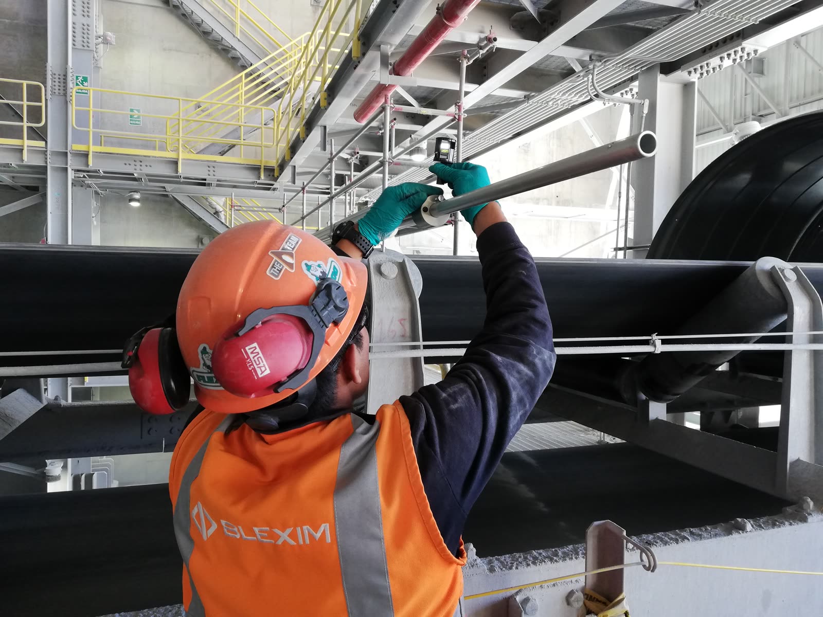 Técnico de Blexim midiendo un componente sobre una faja transportadora en planta