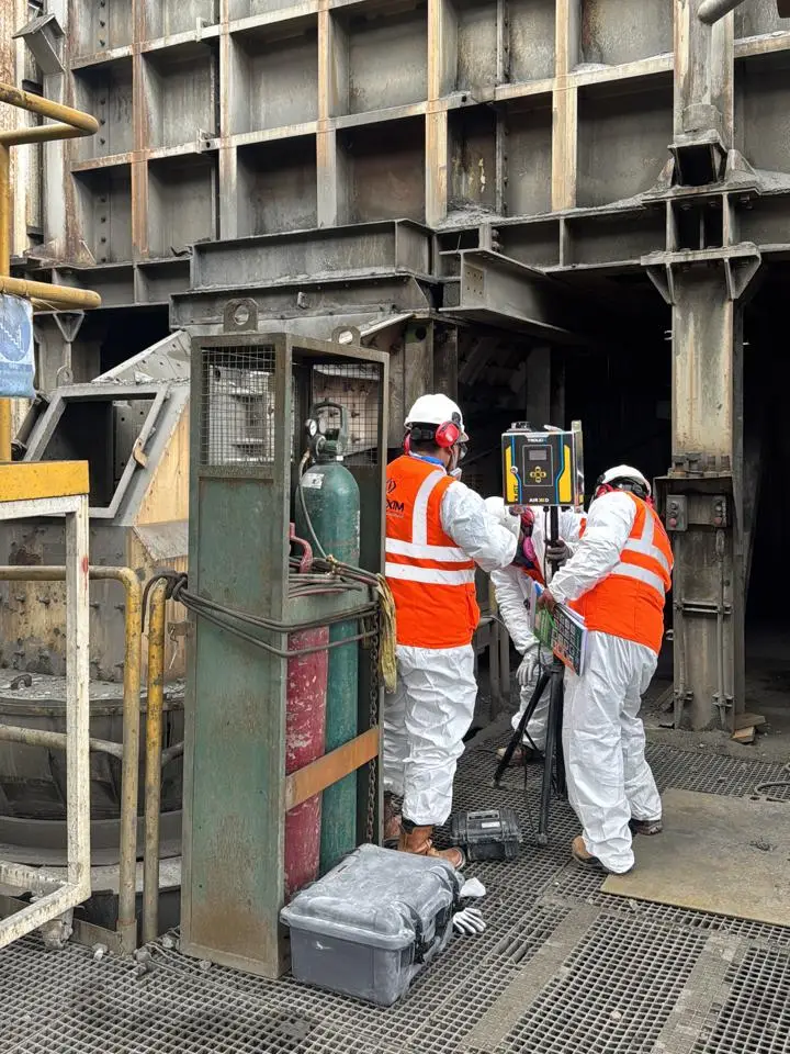 Equipo de Blexim con trajes Tyvek y protección respiratoria instalando un monitor TROLEX AIR XD sobre trípode en un punto crítico de la operación